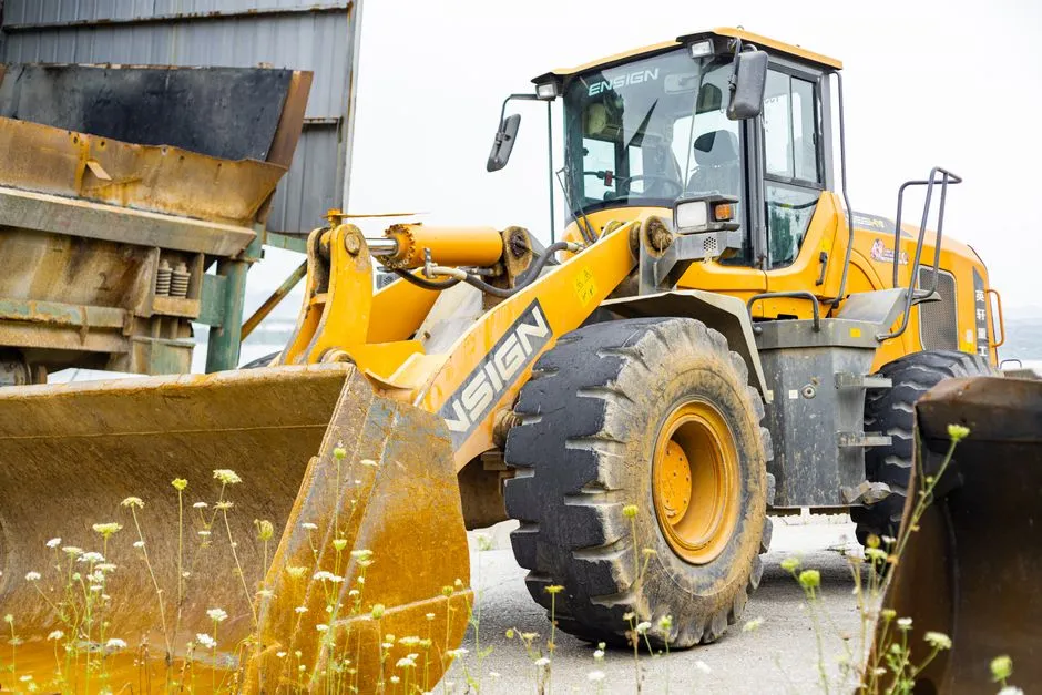 Close-up of an industrial loader in a worksite setting on a clear day, showcasing its massive build and machinery.